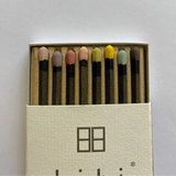 Box of matches with colorful heads on a light gray background